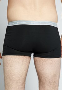 Schwarze Boxershorts mit einem grauen JP1880 Elastikbund. Der Stoff ist glatt, und das Design bietet eine enge Passform mit kurzen Beinen.