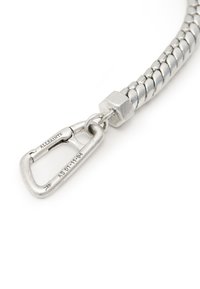 Bracciale in metallo tono argento con design intrecciato. Presenta un collare esagonale e un moschettone. Dettagli incisi sull'hardware.