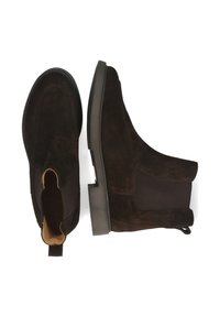 Botas de ante marrón hasta el tobillo con detalles elásticos en los laterales y una lengüeta para tirar. Suela plana de goma y diseño de punta redondeada. Detalle sencillo de costuras.