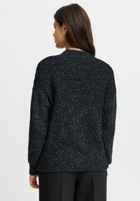 Tamna pletena pulover s teksturiranim uzorkom, rebrastim manžetama i rubom. Ima okrugli izrez i blago oversized dizajn.