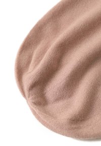 Beanie in magenta chiaro, lavorato a maglia, con una forma leggermente scivolosa e una consistenza liscia, dotato di un bordo a coste e una costruzione senza cuciture.