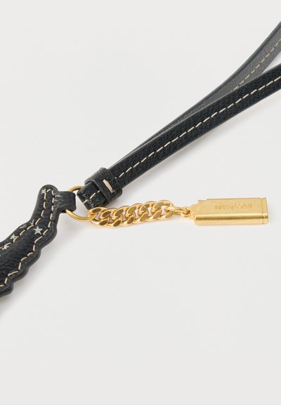 Μαύρο υφασμάτινο λουρί με χρυσά εξαρτήματα, που διαθέτει λεπτομέρεια αλυσίδας και ορθογώνια χρυσή ετικέτα. Λευκό ράψιμο διακοσμεί το λουρί.