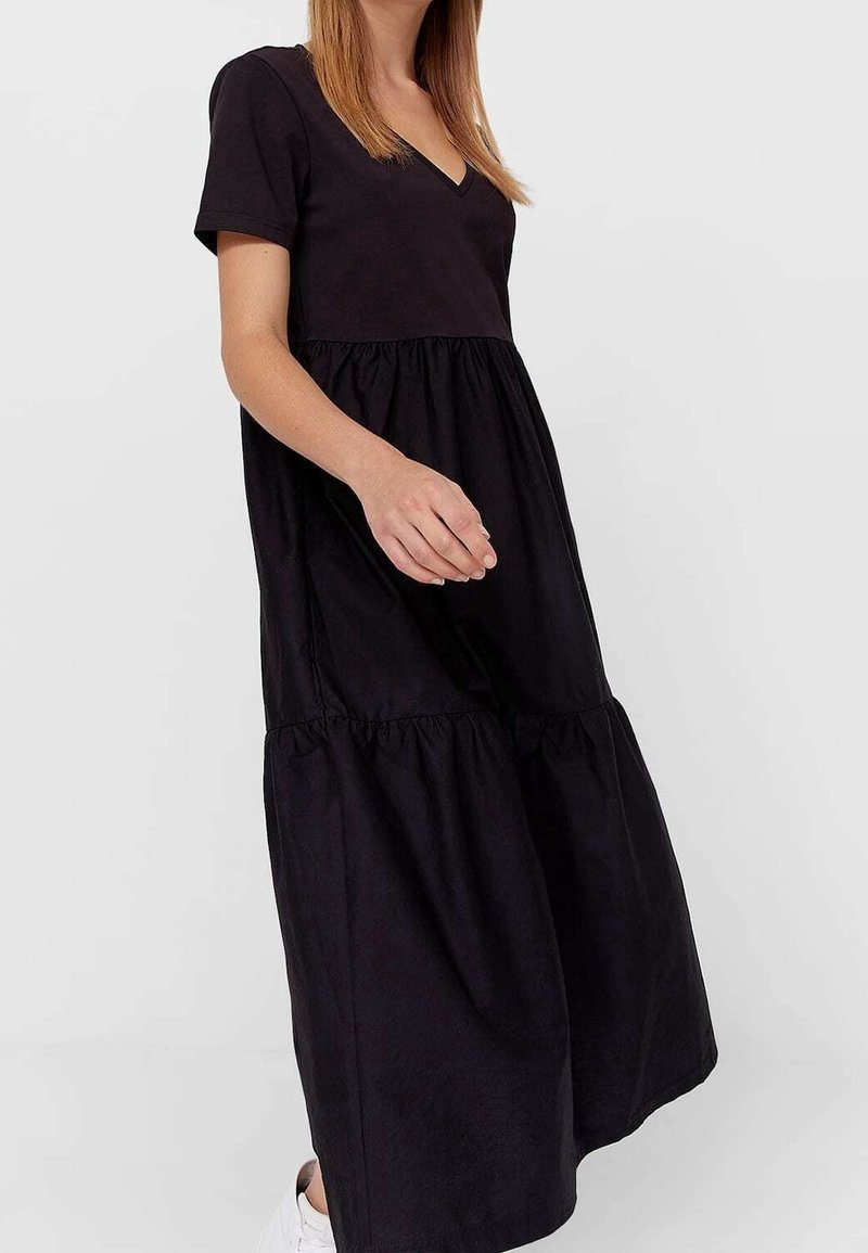 Czarna bawełniana sukienka z krótkimi rękawami, dekoltem w serek, warstwową spódnicą i marszczeniami w pasie. Gładka faktura, do kolan, casualowy styl.