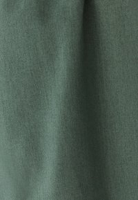 Green linen fabric with a textured surface, featuring a subtle weave pattern and soft drape, suitable for various textile applications.