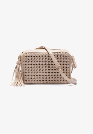 Sac bandoulière beige avec panneau avant tissé, sangle ajustable et tirette de fermeture éclair à pompon sur fond blanc.