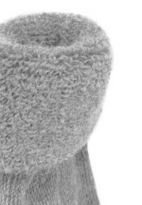 Weiche graue gestrickte Socke mit einem strukturierten, gerollten Bündchen. Hergestellt aus einem flauschigen Garn, das subtile Unterschiede in der Dicke aufweist und ein einheitliches Design präsentiert.