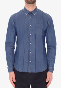 Camicia in denim button-up di colore blu scuro con colletto classico, maniche lunghe e tasca singola sul petto. Presenta bottoni bianchi e cuciture a vista.