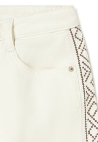 Primer plano de pantalones de mezclilla blancos con bolsillo frontal y franja lateral bordada geométrica marrón.