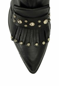 Black leather ankle boot with pointed toe, featuring fringe, metallic studs, and a wide strap embellished with round silver accents.