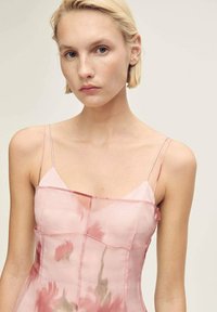 Rochie roz transparentă cu modele florale, bretele subțiri și un design ajustat. Prezintă o textură delicată, transparentă și cusături structurale.
