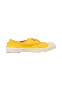 Zapatilla de lona amarilla con suela de goma blanca y punta reforzada, vista de lado sobre un fondo blanco.
