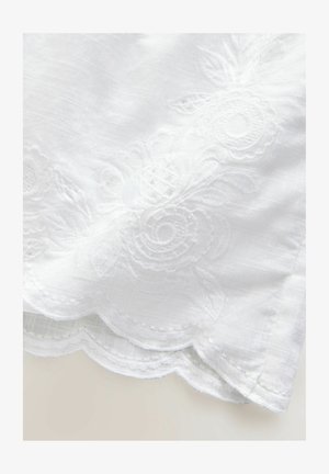 Tissu blanc avec broderies florales, présentant des bords festonnés. La texture est lisse avec un léger éclat. Détails complexes sur le design.