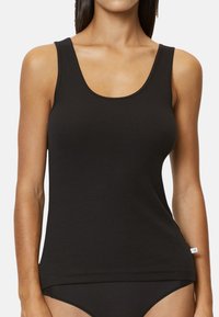 Schwarzes, geripptes Tanktop mit einem runden Ausschnitt und breiten Trägern. Aus weichem, dehnbarem Stoff gefertigt, mit einem geraden Saum und minimalem Branding.