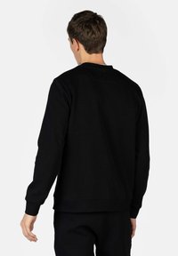 Črna sweatshirt s dolgimi rokavi, okroglo izrezano ovratnikom in rebrastimi manšetami. Ima teksturiran zadnji del in sproščen kroj.