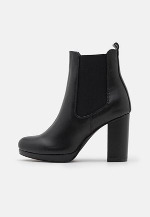 Bottine en cuir noir avec talon bloc, panneau latéral élastique et languette, présentée en profil droit sur fond blanc.