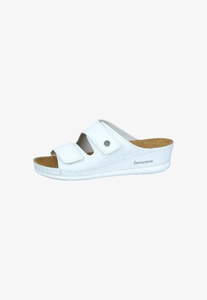 White slide sandal with two adjustable hook-and-loop straps, cork insole, and rubber outsole. Features a rounded toe and slight heel.
