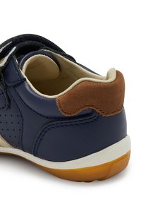 Marineblaue Lederschuhe mit einem Akzent aus hellbraunem Wildleder an der Ferse, weißer Zwischensohle und dunklen Schnürsenkeln. Verfügt über Perforationen an den Seiten und eine strukturierte Gummisohle.