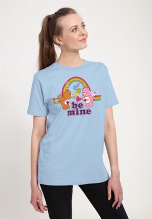 Lysblå bomulds t-shirt med et farverigt grafik af to bjørne omgivet af hjerter og en regnbue, med teksten "vær min" trykt nedenfor.