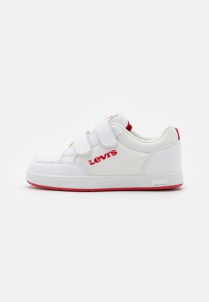 Baskets blanches pour enfants avec semelle rouge, deux bandes Velcro, et logo Levi's rouge sur le côté et sur la languette arrière.