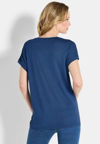 Marineblaues kurzärmliges T-Shirt mit lockerem Schnitt, aufgerollten Ärmeln und glatter Textur. Die Rückansicht zeigt ein einfaches, sauberes Design.