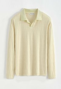 Chemise jaune pâle à manches longues avec un col classique, présentant un motif texturé de lignes verticales et une coupe légèrement décontractée.