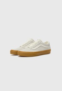 Sneaker mit einem kremfarbenen Canvas-Obermaterial, kontrastierendem weißen Streifen und brauner Gummisohle. Verfügt über klassische Schnürung und runde Zehenform.