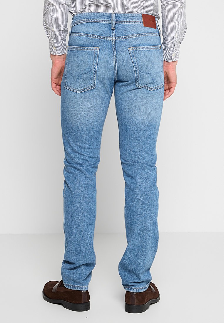 Jeans de mezclilla de color azul claro con corte recto, que cuentan con dos bolsillos traseros, costuras sutiles y una etiqueta de cuero marrón en la cinturilla.