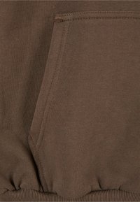 Tejido de sudadera marrón con dobladillo acanalado y un bolsillo frontal. El material presenta una textura suave con costuras visibles.