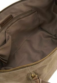 Interno di una borsa in suede marrone con una texture liscia, dotato di una tasca con zip e numerosi scomparti, con hardware della zip in oro.