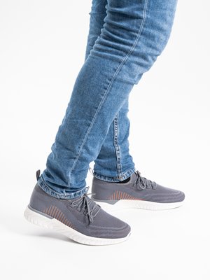 Legs wearing blue jeans and gray mesh sneakers with white soles, standing against a white background.