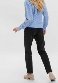 Ljusblå kabelstickad tröja, svarta jeans och beige plattformsskor. Fokusera på stickad textur och avslappnad denim silhuett.