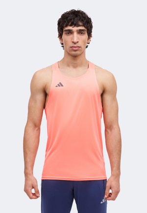 Man draagt een mouwloos koraalrood sporttopje met logo en marineblauwe shorts, staand, vooruit kijkend met een neutrale gezichtsuitdrukking tegen een witte achtergrond.