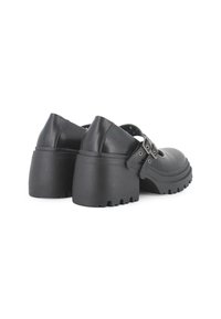 Zapatos de plataforma de cuero negro con punta redonda, suela gruesa y detalle de hebilla en la correa. Acabado texturizado con dibujo pronunciado.