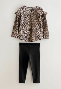 Langärmliges Oberteil im Leopardenmuster mit Rüschensäumen, kombiniert mit schwarzen Leggings. Das Oberteil hat einen runden Halsausschnitt und einen Druckknopfverschluss hinten.