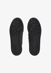 Svarta gummiskosulor med ett cirkulärt och texturerat mönster, med framträdande varumärke och spår för grepp.