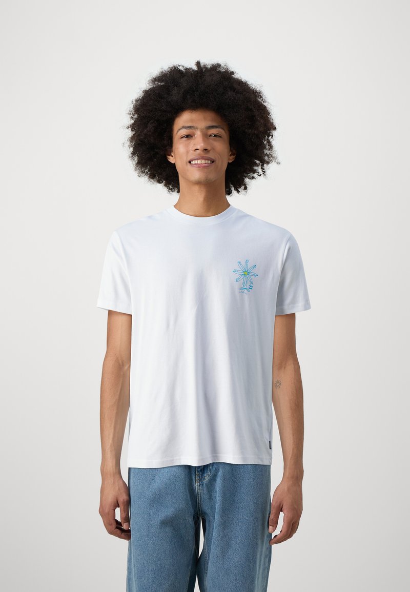 Witte katoenen t-shirt met korte mouwen, voorzien van een blauw grafisch ontwerp op de linker borst. Draag het met lichtblauwe spijkerbroek.
