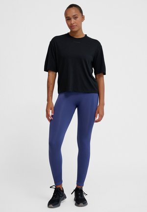 Black cropped t-shirt made of soft fabric, paired with fitted purple leggings. The leggings have a smooth texture and a high-waisted design.