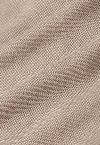 Lichtbeige geweven stof met een textuurovervlak. Het materiaal toont een fijn rasterpatroon en een subtiele glans.