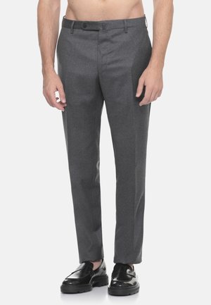 Pantaloni grigi su misura con taglio dritto, realizzati in un tessuto liscio, dotati di chiusura con bottone e tasche laterali. Indossati con scarpe nere.