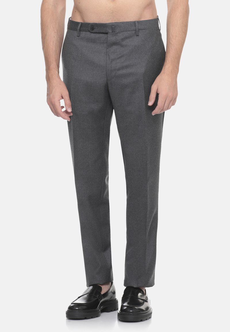 Pantaloni grigi su misura con taglio dritto, realizzati in un tessuto liscio, dotati di chiusura con bottone e tasche laterali. Indossati con scarpe nere.