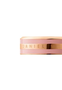 Orologio metallico con cinturino in ceramica rosa e dettagli in oro rosa; presenta il testo inciso "DANIEL WELLINGTON" e una forma rettangolare liscia.