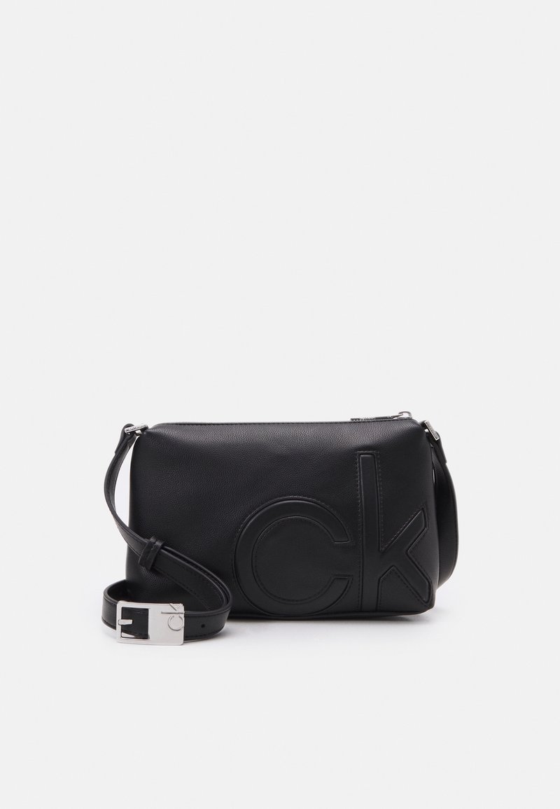 Borsa a tracolla nera in pelle con logo "CK" in rilievo, texture liscia, hardware in argento, tracolla regolabile, forma rettangolare.
