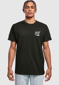 Sort bomulds t-shirt med hvid grafisk tryk på venstre bryst. Rund halsudskæring og korte ærmer. Afslappet pasform.