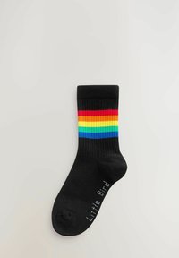 Calza di cotone nera con un design a coste caratterizzato da strisce orizzontali arcobaleno in rosso, arancione, giallo, verde, blu e viola. "Little Bird" stampato in bianco.