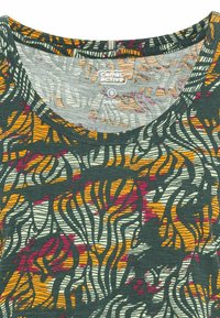 Chemise à manches courtes dotée d'un motif abstrait multicolore dans des tons de vert foncé, orange, rouge et blanc. Fabriquée en tissu organique avec un col ras du cou.