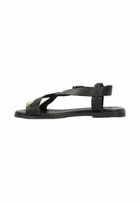 Black sandal with crisscross strap design, flat sole, smooth texture, adjustable back strap, and gold accents on front.