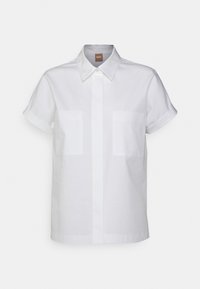 Camisa blanca de manga corta con botones, dos bolsillos en el pecho delantero y un cuello puntiagudo, presentada sobre un fondo liso.