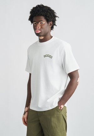 Hvid bomulds-T-shirt med grøn broderet "DICKIES"-logo på brystet. Figursyet design, rund halsudskæring, korte ærmer og blød tekstur.