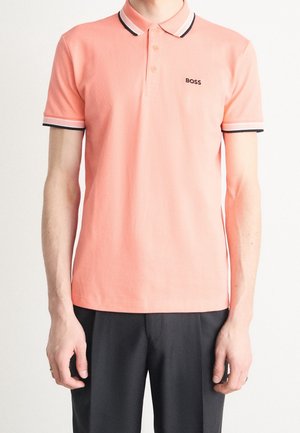 Orange polo-shirt med krave, med kontrasterende sorte og hvide striber på kraven og ærmekanterne. Logo på venstre bryst.