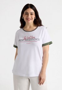Weißes Baumwoll-T-Shirt mit grünen Akzenten, Rundhalsausschnitt und kurzen Ärmeln. Der Text auf der Vorderseite lautet: "Die beste Zeit für NEUE ANFÄNGE IST JETZT."